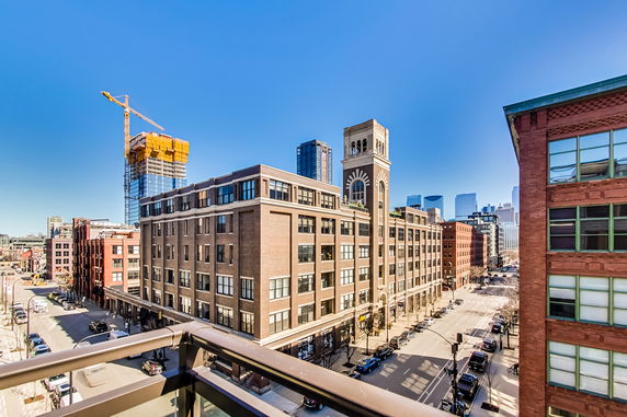 Panoramic view of a cityscape with multiple buildings including a construction site, viewed from a balcony.