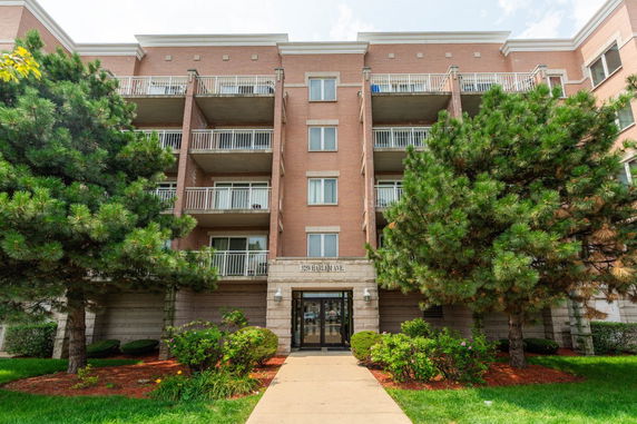 Front view of a multi-story brick apartment building with balconies and a central entrance.