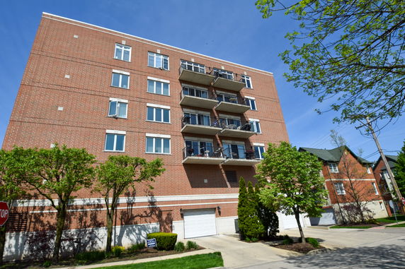 Front view of a multi-story brick apartment building with balconies and garages.
