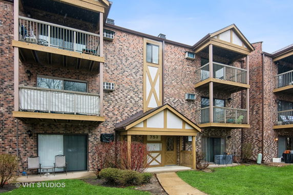 Front view of a multi-story brick apartment building with balconies.