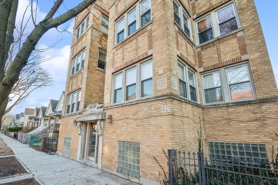 Front view of a multi-story brick building with decorative stonework around the entrance.