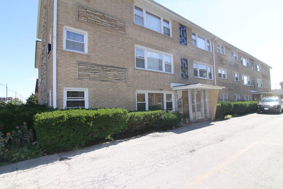 Front view of a three-story brick apartment building with a glass entryway.