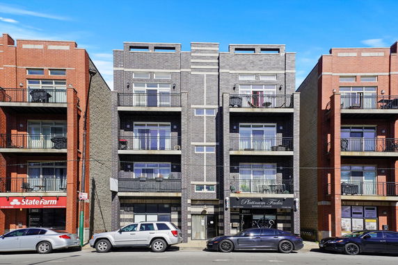 Front view of a multi-story residential building with balconies and commercial units on the ground floor.