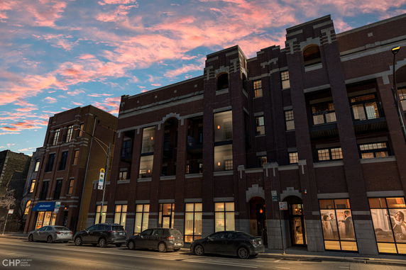 Front view of a multi-story brick building with large windows and an arched design.