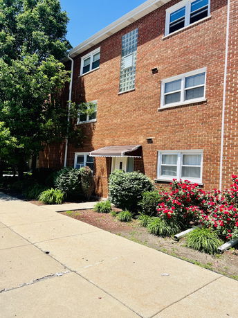 Front view of a three-story brick building with multiple windows and a small entrance.