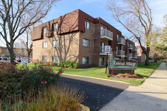 Front view of a multi-story condominium building with balconies and a brown brick facade.