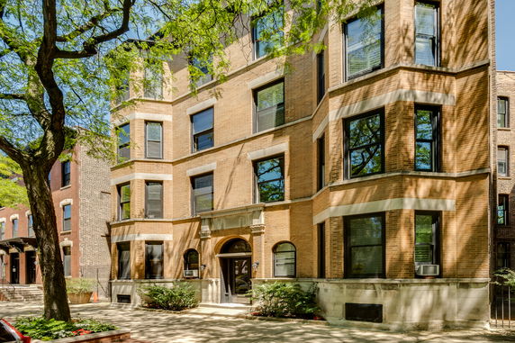 Front view of a multi-story brick building with bay windows.