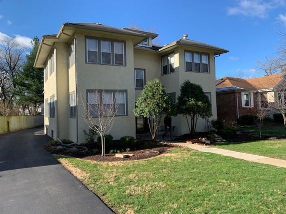 Front view of a two-story residential house with multiple windows and a driveway.