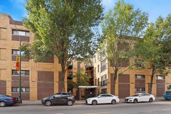 Front view of a multi-story apartment building with brown and beige brick exterior.