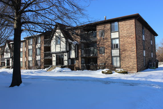 Front view of a three-story apartment building with brick exterior and balconies.