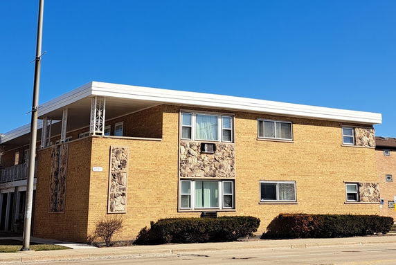Front view of a two-story residential building with brick facade and decorative stone panels.