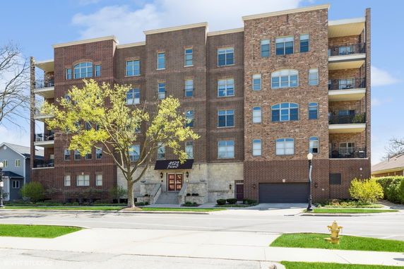 Front view of a multi-story brick apartment building with balconies.