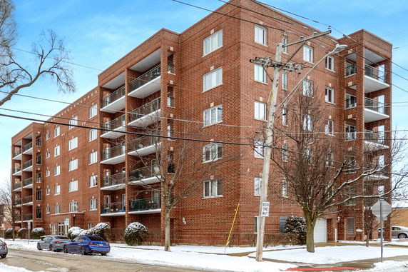 Front view of a multi-story brick apartment building with balconies.