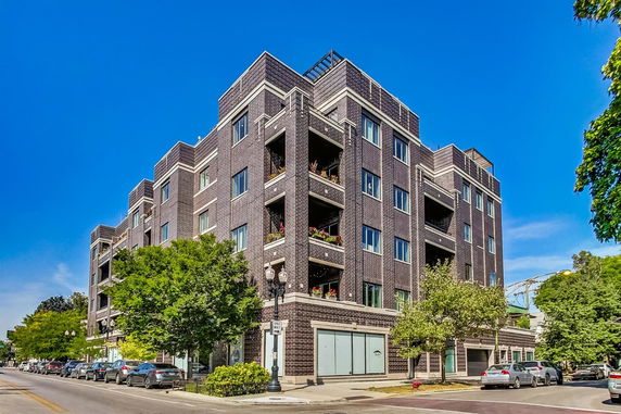 Front view of a multi-story brick apartment building with balconies.