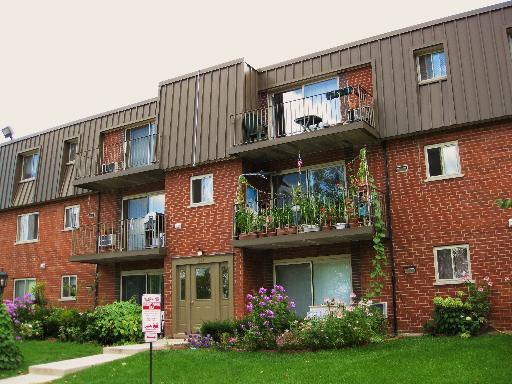 Front view of a multi-story brick apartment building with balconies.