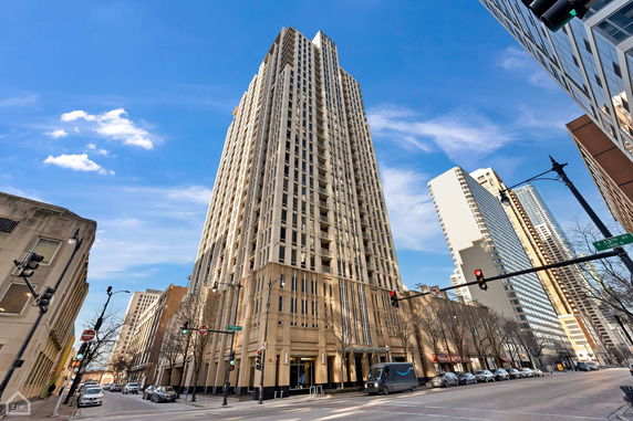 Front view of a tall residential skyscraper building with multiple balconies and a modern facade.