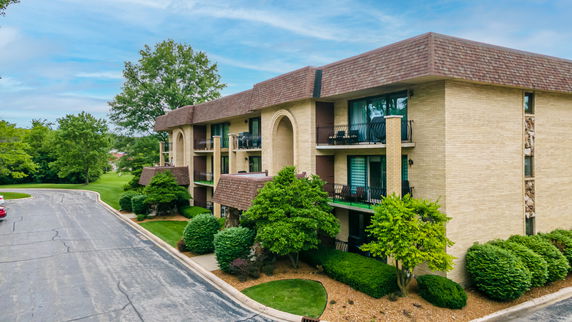 Front view of a multi-story building with balconies and a shingled roof.