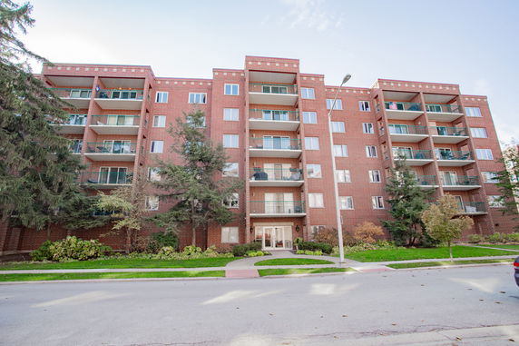Front view of a multi-story brick apartment building with balconies.