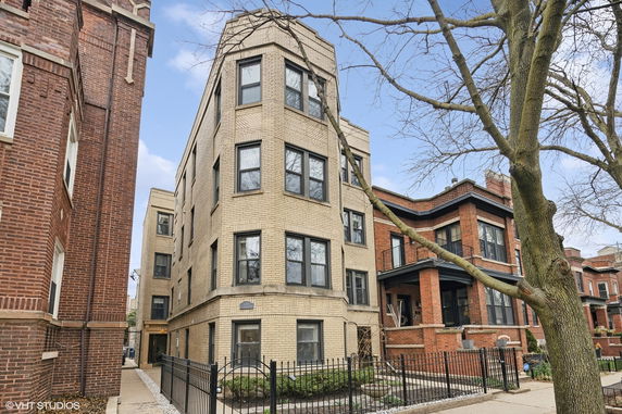 Front view of a multi-story residential building with a beige brick facade.