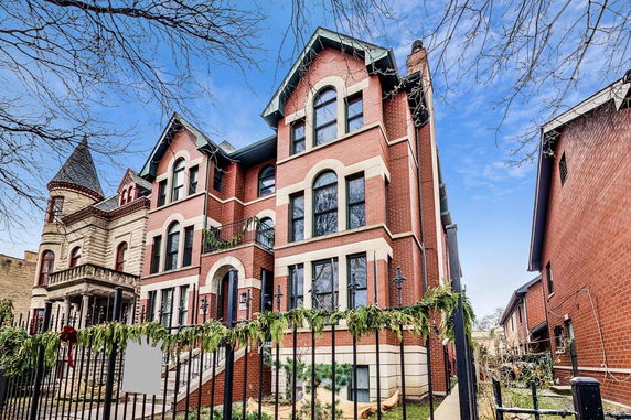 Front view of a multi-story brick building with decorative elements and large windows.