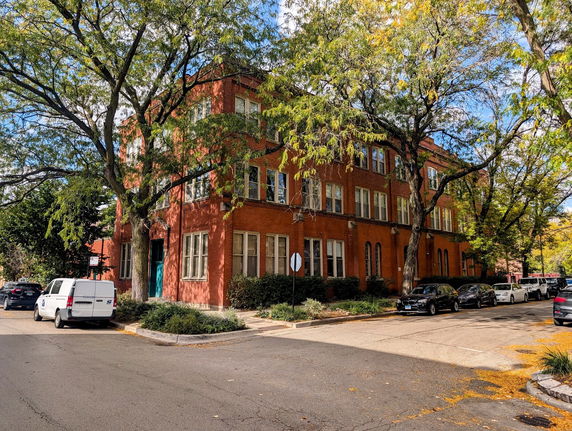 Front view of a three-story brick building on a street corner.