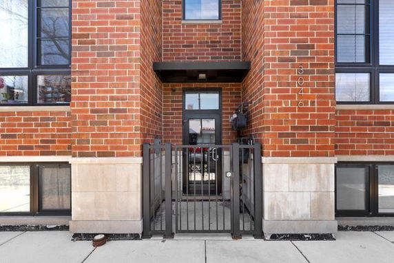 Front view of a brick facade building entrance with a metal gate.