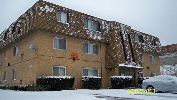 Front view of a three-story apartment building with a snowy roof.