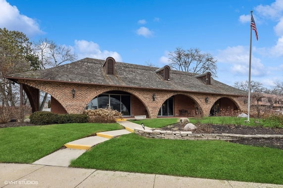 Front view of a brick building with unique arched entrances and a shingled roof.