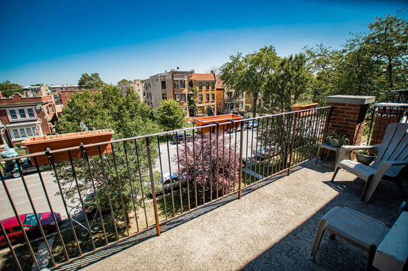Panoramic view from a balcony showing surrounding buildings and trees.