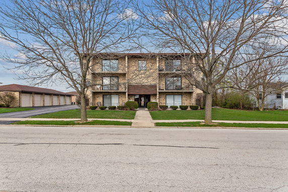 Front view of a three-story brick apartment building with balconies.