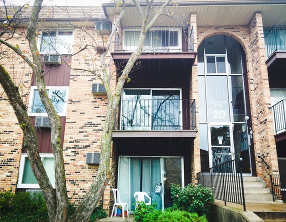 Front view of a multi-story brick residential building with balconies.
