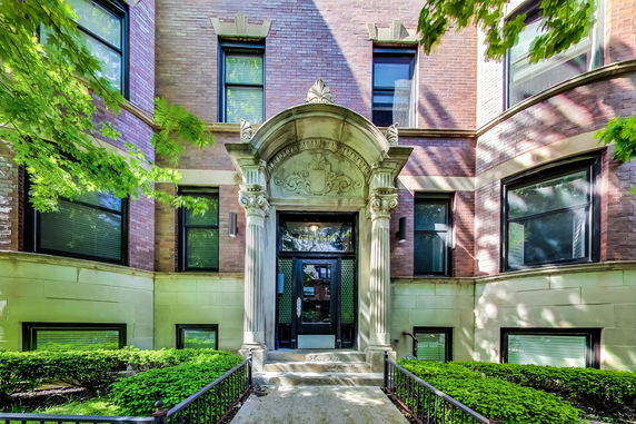 Front view of a brick building with decorative entrance and large windows.