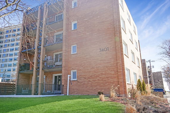 Front view of a multi-story brick apartment building with balconies.