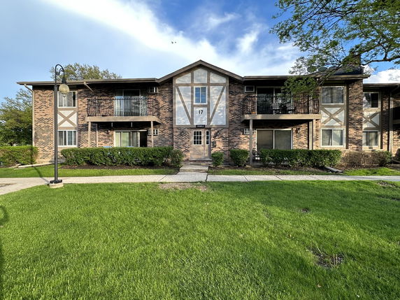 Front view of a two-story apartment building with brick facade and balconies.