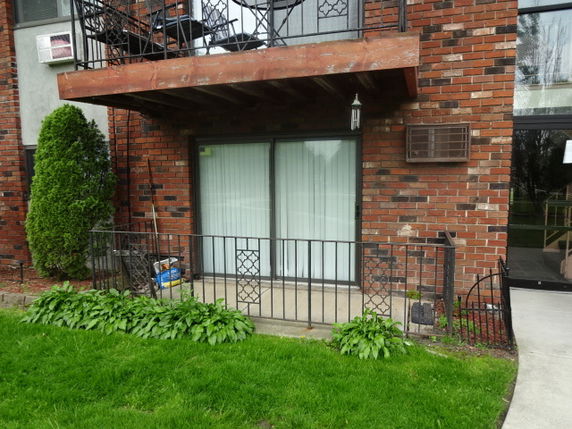 Front view of a building with a balcony and sliding glass door.