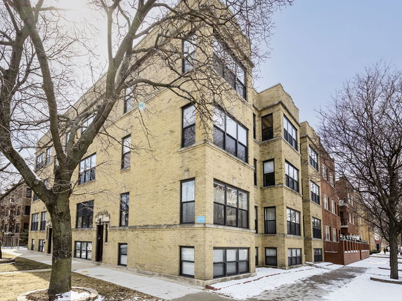 Front view of a multi-story brick building with large windows.