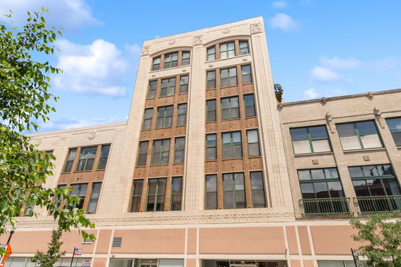 Front view of a multi-story building with decorative facade and large windows.