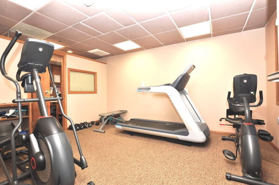 Indoor gym area with exercise equipment including a treadmill, exercise bike, and weights.