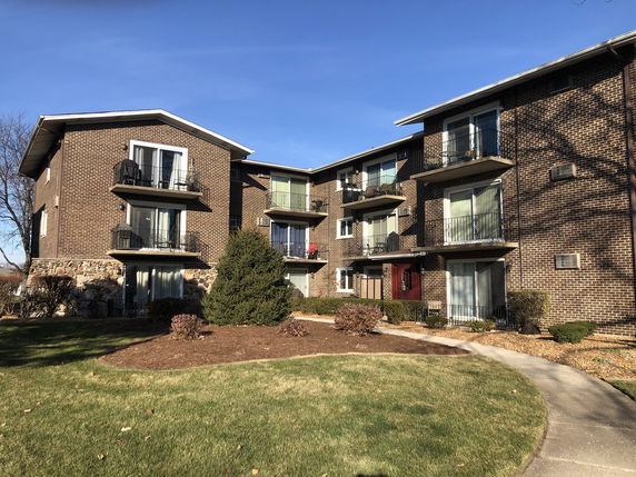 Front view of a multi-story apartment building with brick exterior and balconies.