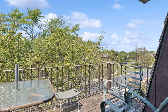 View from a balcony showing trees and a distant street.