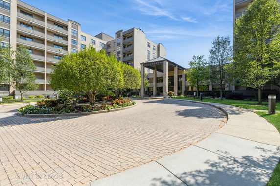Front view of a multi-story building with a landscaped entrance and circular driveway.
