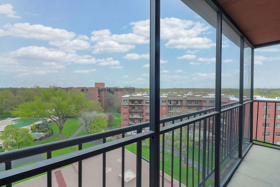Panoramic view from a building balcony overlooking surrounding buildings and greenery.