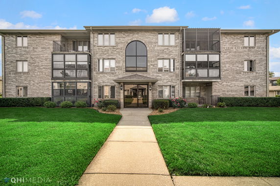 Front view of a multi-story brick building with a central entrance and large windows.