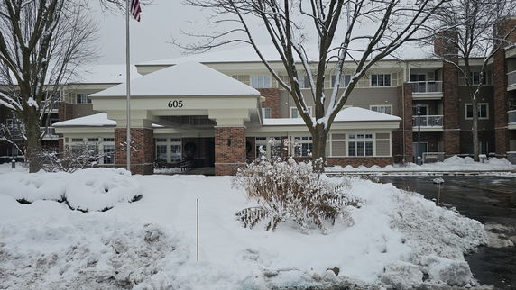 Front view of a multi-story building with snow-covered entrance and surroundings.