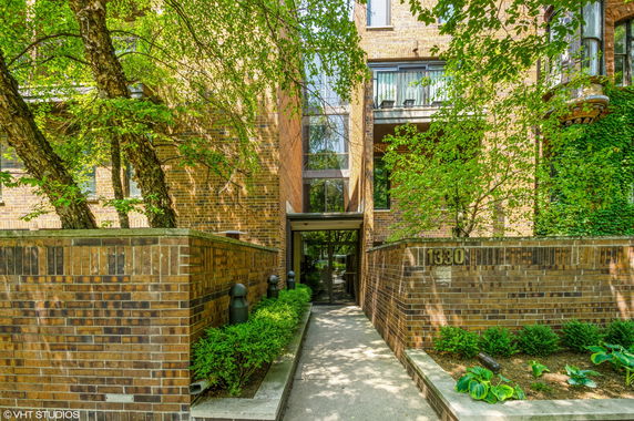Front view of a brick residential building with trees and greenery.