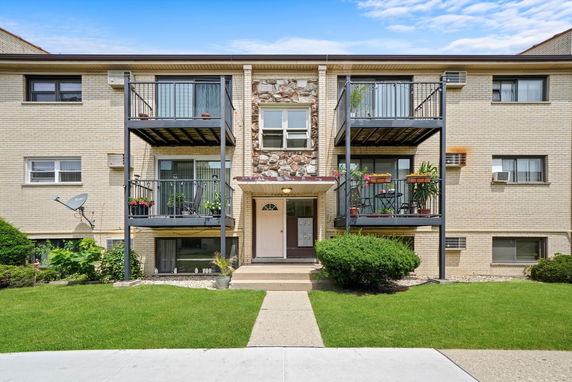 Front view of a multi-story apartment building with balconies.