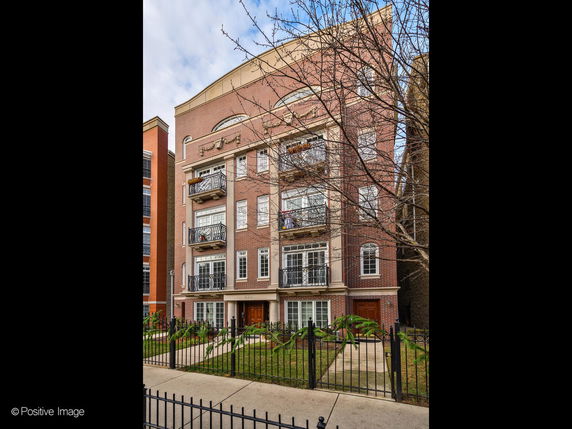 Front view of a multi-story brick apartment building with balconies.