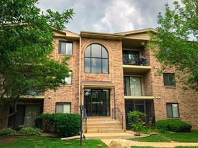 Front view of a multi-story brick apartment building with large central windows and balconies.