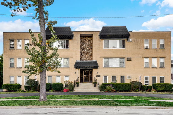Front view of a rectangular three-story apartment building.