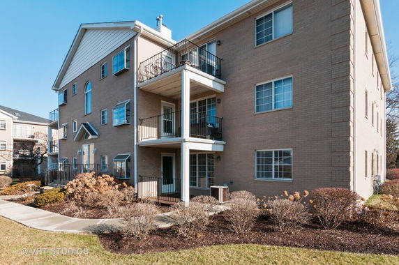 Front view of a multi-story brick apartment building with balconies and large windows.